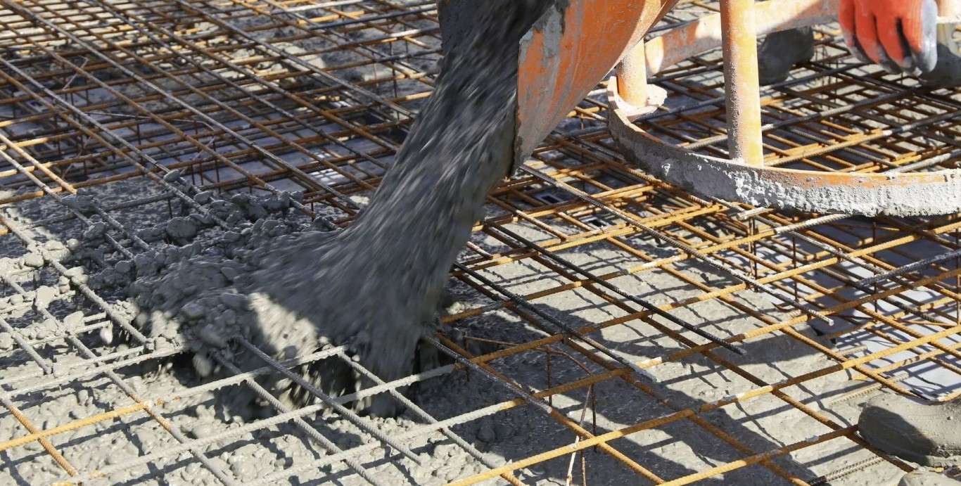 Concrete being poured over rebar reinforcement for durable foundation
